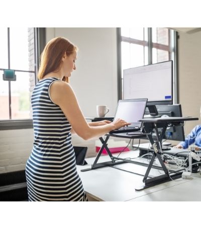 woman in striped dress working at a sit-to-stand table top desk 