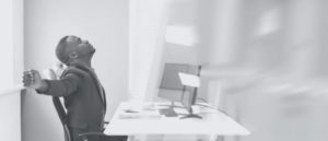 man stretching while sitting at desk