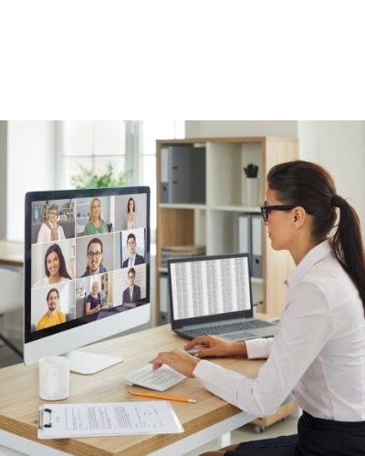 woman sitting in front of one monitor with laptop to her right